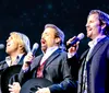 The image showcases three men dressed in cowboy hats and suits identified as The Texas Tenors against a sparkling starry background