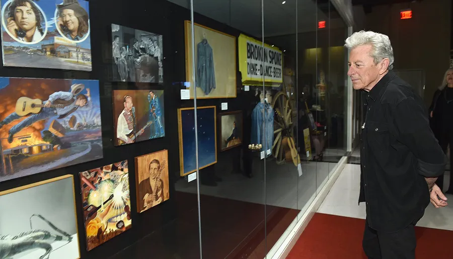 A person is walking past a display of various artworks and memorabilia.