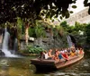 Tourists enjoy a boat ride in an enclosed space with lush vegetation and a waterfall in the background