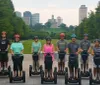 Two individuals are smiling for the camera while riding Segways on a path with the Nashville skyline in the background