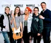 Five people are posing for a photo with smiles at a Nashville Studio Tour event where one person is holding a guitar