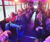 A group of people are sitting on a bus with purple lighting some smiling and clapping suggesting a lively atmosphere