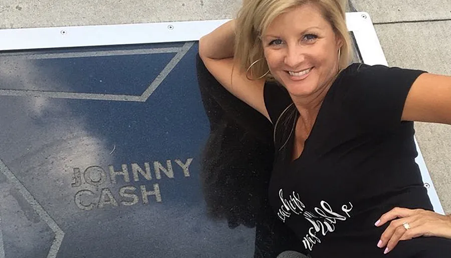 A smiling woman poses next to a star on a walkway that reads JOHNNY CASH.