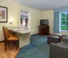 This image shows a clean and well-arranged hotel room with two beds a desk with an office chair and a television