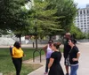 A group of people is standing on a sidewalk reading a historical marker titled Nashville Sit-Ins in an urban setting