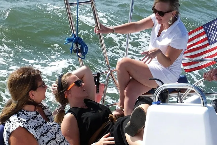 Three people are enjoying a sunny day on a sailboat with the American flag visible in the background.