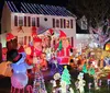 The image shows an elaborately decorated house for Christmas with numerous colorful lights inflatable characters and figures that create a festive and vibrant holiday scene