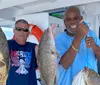 Two smiling men are posing on a boat each holding up a large fish they seemingly caught