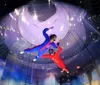 Two people are indoor skydiving in a vertical wind tunnel seemingly enjoying an exhilarating flying experience