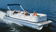 A group of people are enjoying a sunny day on a pontoon boat cruising on a calm body of water.