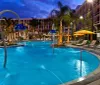 An illuminated and inviting hotel pool area at twilight with lounge chairs and artistic water features creates a serene leisure ambiance