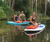 Three people are enjoying paddleboarding on a calm river surrounded by lush greenery