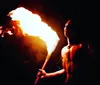 Performers engage in a dynamic fire dance exhibiting cultural tradition and skill against a vivid red backdrop