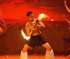 Performers engage in a dynamic fire dance exhibiting cultural tradition and skill against a vivid red backdrop