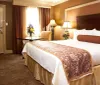 The image shows a tidy and cozy hotel room with a large bed patterned bedspread table with flowers and classic decor