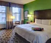 This image shows a modern hotel room with a bed desk chair and a bright green accent wall