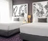 The image shows a modern and stylish bedroom with two neatly made beds distinctive black and white artwork above and a color scheme dominated by purple and grey tones