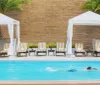 The image features a serene poolside area with loungers and a bar called Bywater Pool Deck  Bar where an attendant is present behind the counter