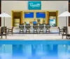 The image features a serene poolside area with loungers and a bar called Bywater Pool Deck  Bar where an attendant is present behind the counter