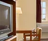 The image shows a neatly arranged hotel room with two beds a television a work desk and decorative wall art