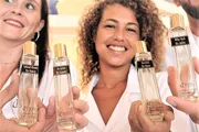 Two joyful women are showcasing bottles of perfume with personalized names on the labels.