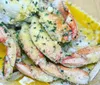 The image shows a dish of seasoned crab legs with herbs and melted butter