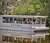 A group of people are enjoying a sightseeing tour on a flat-bottomed boat named Lil Cajun through a tree-lined waterway