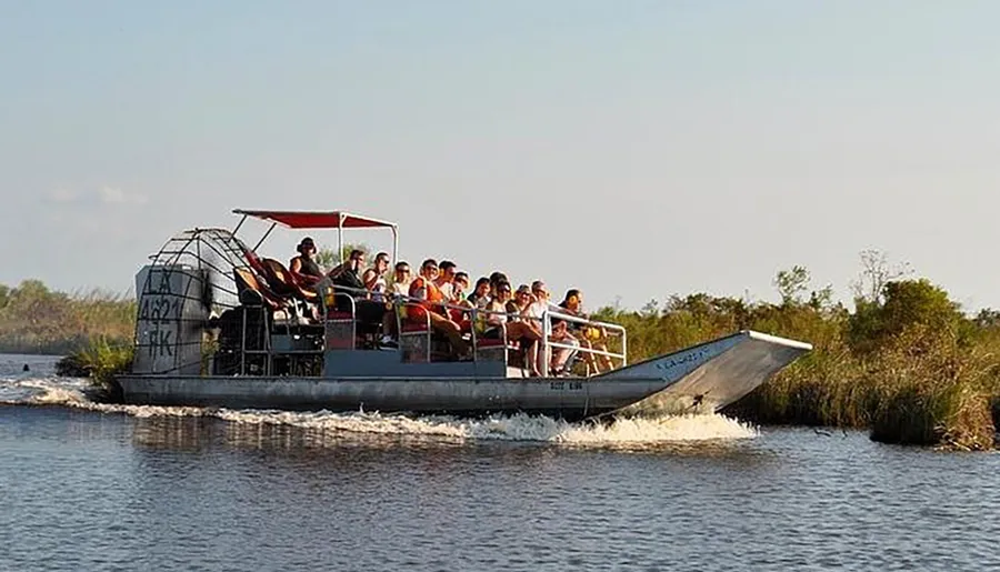 A group of tourists are enjoying a ride on an airboat through a wetland area.