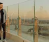 A man and a woman are enjoying a sunset view over an industrial skyline reflected on a glass barrier