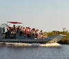 Passengers are enjoying a sunny airboat tour with several wearing ear protection possibly indicating the high noise levels of the boat engine