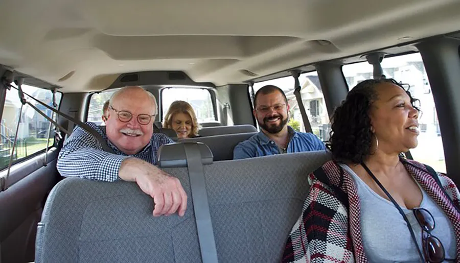 Four people are smiling and enjoying a ride together in a vehicle with a pleasantly lit interior.
