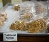 The image shows a tray of traditional pralines individually wrapped in plastic displayed for sale with a label in front