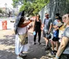 A person dressed in a nun costume gives a tour to a group of attentive tourists on a sunny day on an urban street