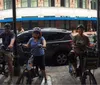 A group of people wearing helmets are standing with their bicycles on a city street ready for a biking activity