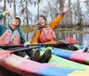 Two happy people are kayaking together in a colorful tandem kayak waving cheerfully in a scenic wetland environment