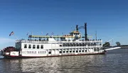 The image shows a traditional paddle-wheel riverboat named the 