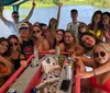 A group of young adults is enjoying a sunny day on a boat posing with drinks and smiling for a group photo