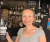 A smiling woman is holding a cup with text in a bar standing next to a man with a Sedona Harley-Davidson t-shirt