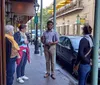 A tour guide appears to be explaining something to a group of attentive tourists on a city sidewalk