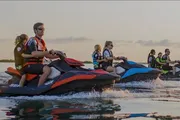 A group of people are riding jet skis on the water, seemingly in a coordinated activity or tour.