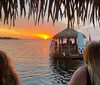 A group of people enjoys drinks on a floating tiki bar boat at dusk