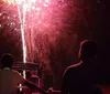 Spectators on a boat watch a vibrant display of fireworks exploding in the night sky