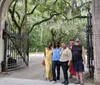 A group of people are posing for a photo at an open gate surrounded by lush greenery and draped Spanish moss