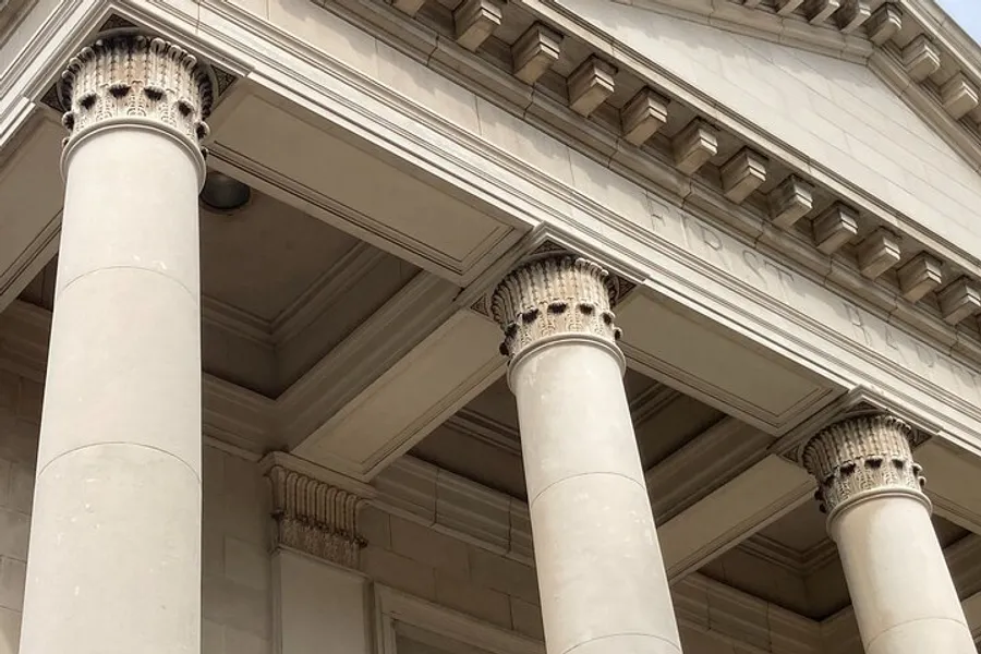 The image shows a close-up of a classic architectural structure with a focus on Corinthian columns supporting a detailed entablature.