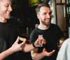 Two men are smiling and holding slices of lime and a shot glass appearing to be enjoying a social moment at a bar