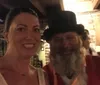 A woman and a man with a beard and top hat are taking a friendly selfie together
