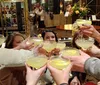 A group of people smiling and toasting with drinks appears to be enjoying a social gathering