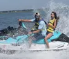 Two people are enjoying a thrilling ride on a jet ski with water spraying around them