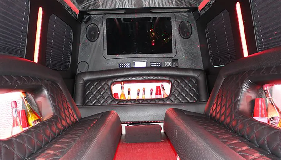 The image shows the luxurious and modern interior of a limousine with red accent lighting, comfortable seating, and a built-in bar area.
