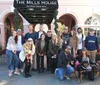 A group of smiling people some with dogs are posing for a photo in front of The Mills House Wyndham Grand Hotel